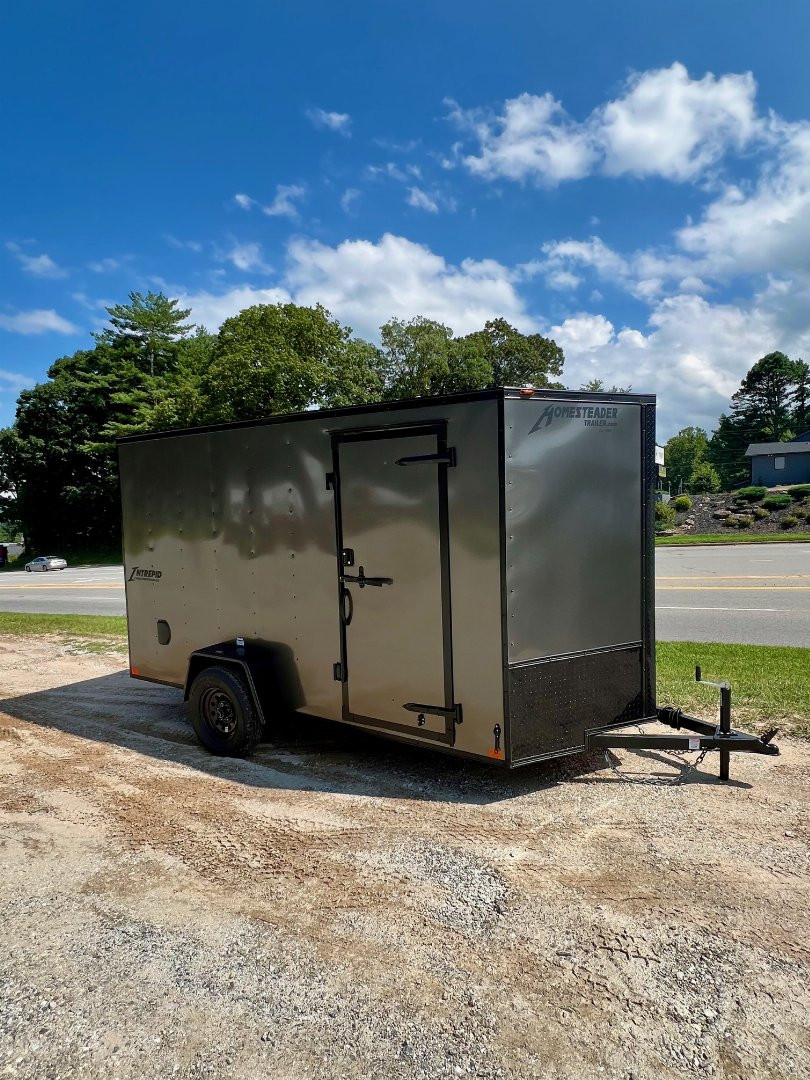 New 2025 HOMESTEADER TRAILER / INTREPID SERIES / 6' WIDE X 12' LONG / 6'6" INTERIOR HEIGHT / .030 CHARCOAL GRAY ALUMINUM W/ BLACK OUT PKG / 32" SIDE DOOR W/ RV LOCK / RAMP REAR DOOR / 4-D RINGS / 16" O/C WALL POST